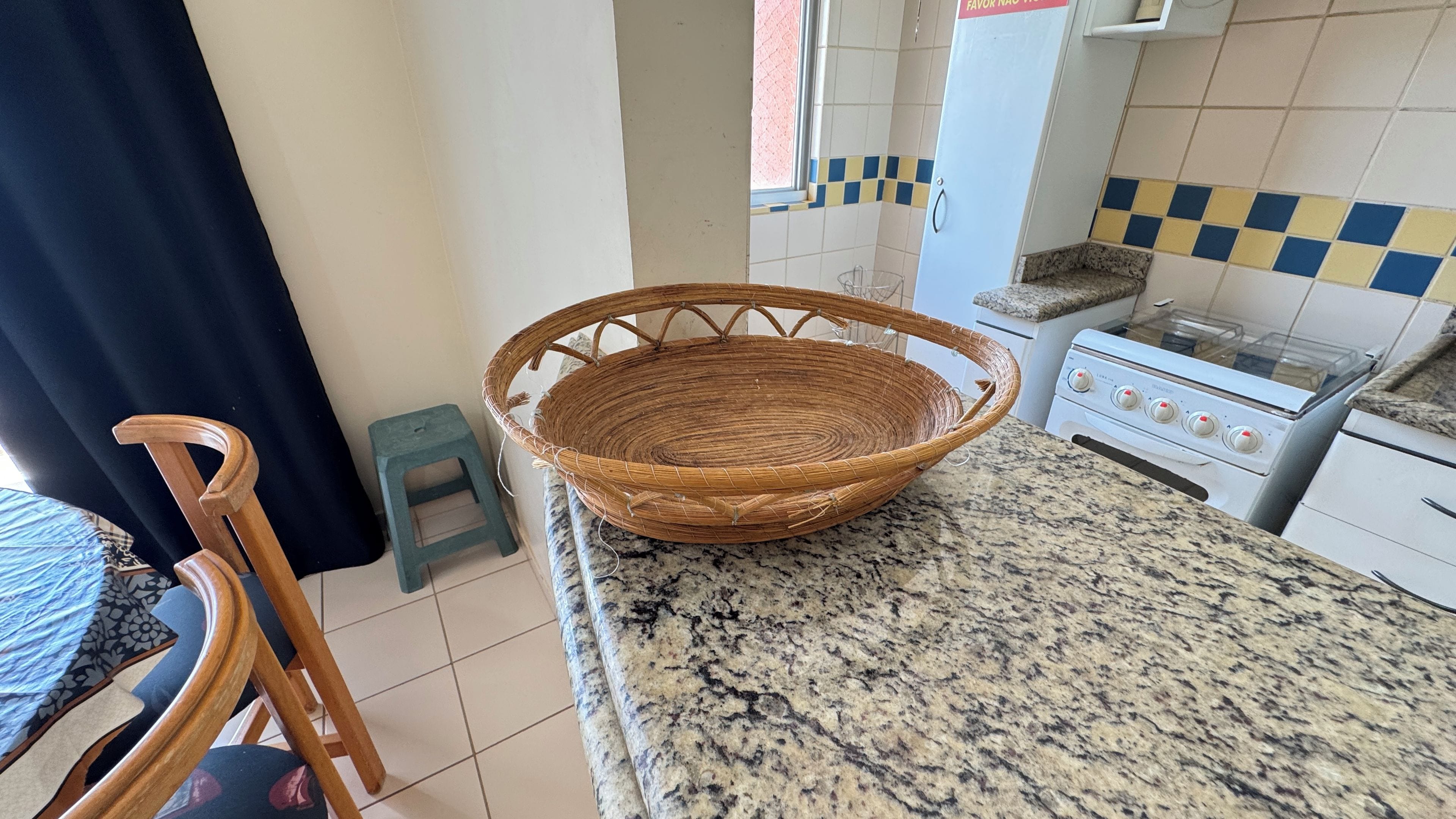 Una cocina con encimera de granito, una cesta de mimbre, un taburete pequeño y una estufa.
