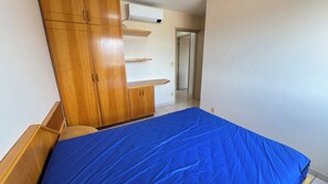 Un dormitorio con cama, armario de madera y pared blanca.