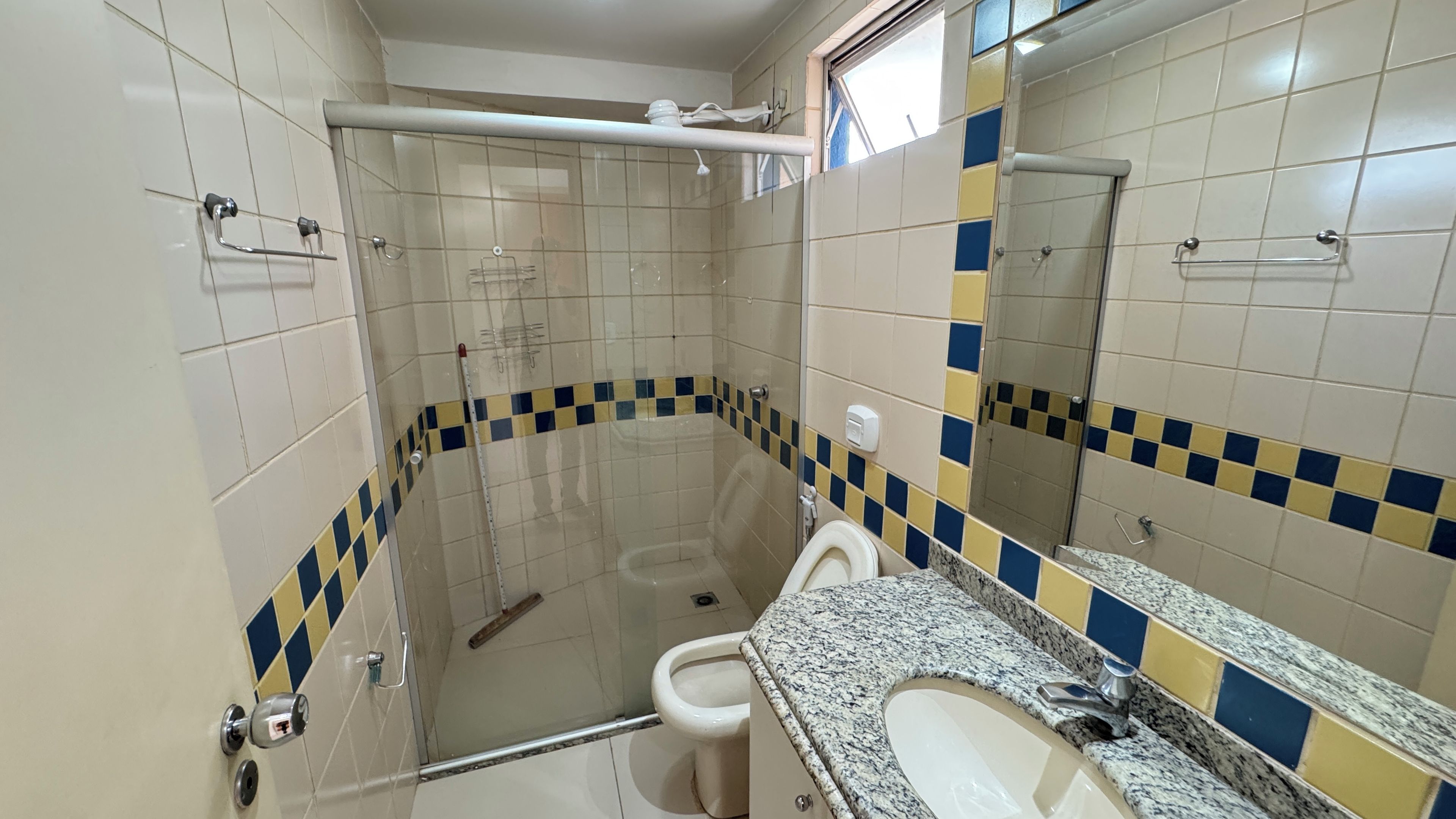 Een badkamer met een douchecabine, een toilet en een wastafel met een granieten blad.