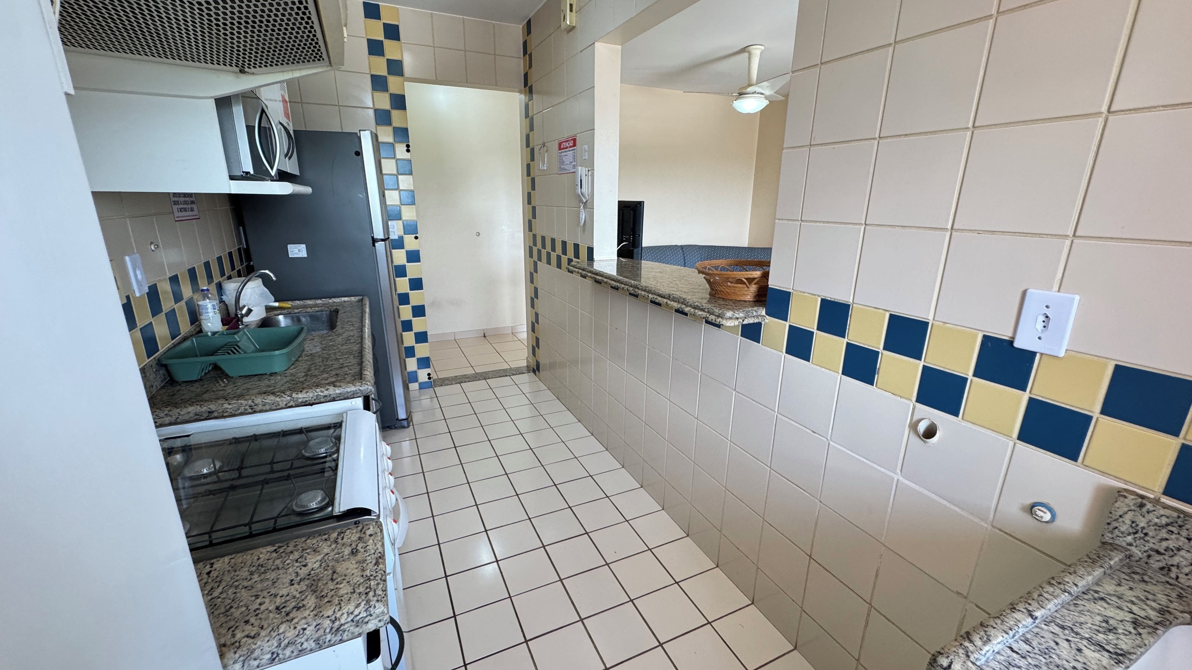 Um corredor estreito com uma área de cozinha de um lado, incluindo pia, bancada e fogão.