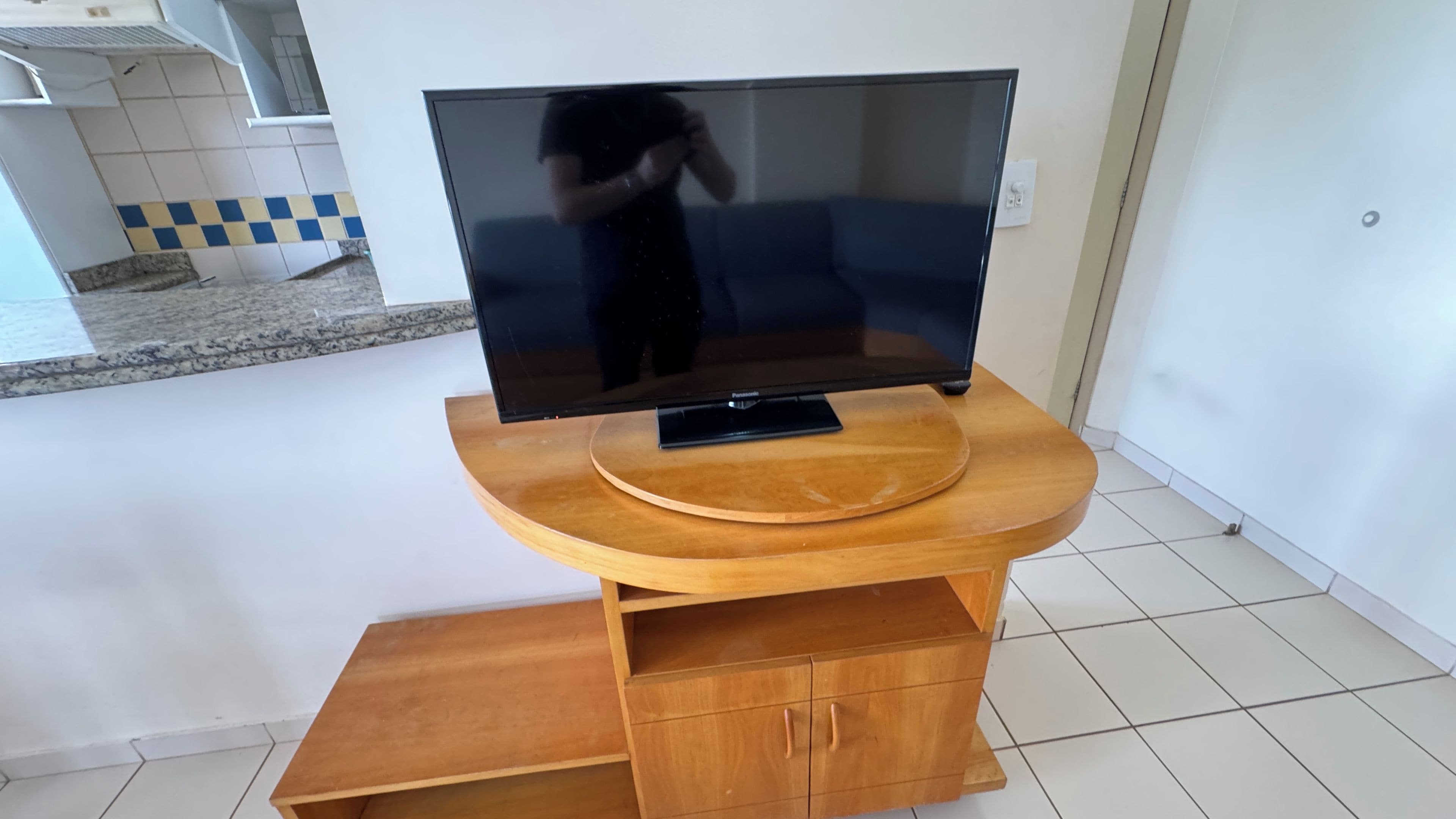 Televisão de tela plana em móvel de madeira com armário na parte inferior.