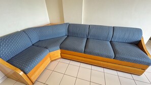 A corner sectional sofa with a geometric pattern, wooden frame, and a tiled floor. - CRCN - Thermas das Caldas (Caldas Novas)