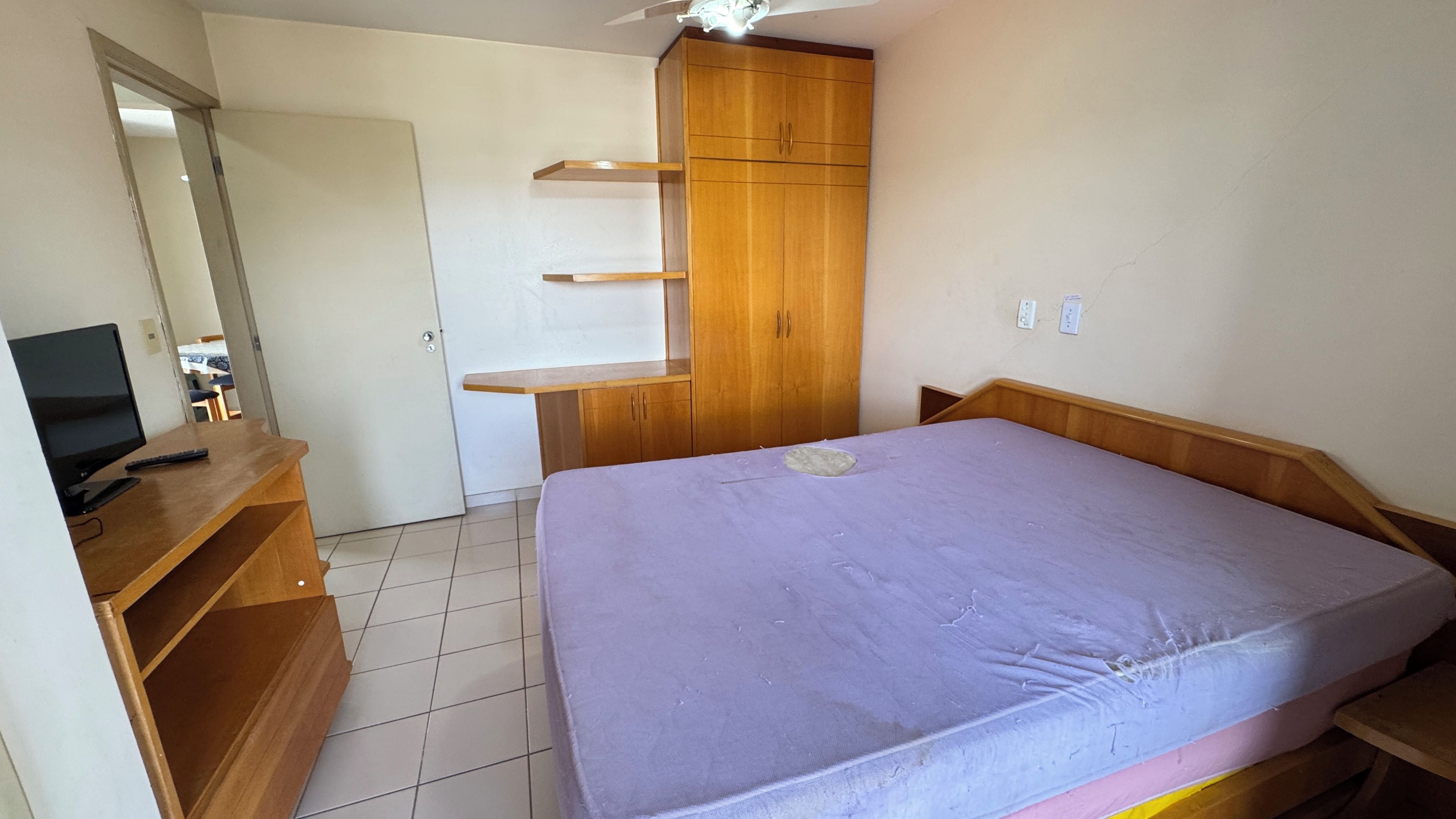 A bedroom with a bed, a desk with a computer, a wardrobe, and a mirror.