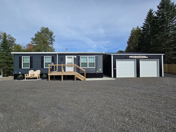A two-story building with a front porch, a garage, and a small attached shed.