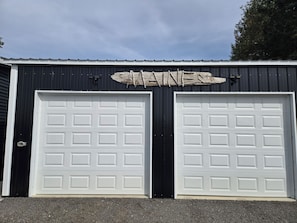 A building with two white garage doors and a sign above them.