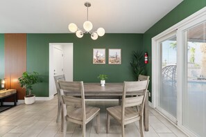 Ein Essbereich mit Holztisch und -stühlen, einer Pendelleuchte und zwei gerahmten Bildern an der Wand.