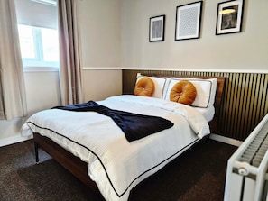 Ein Hotelzimmer mit einem Bett, einem Heizkörper und drei gerahmten Bildern an der Wand.