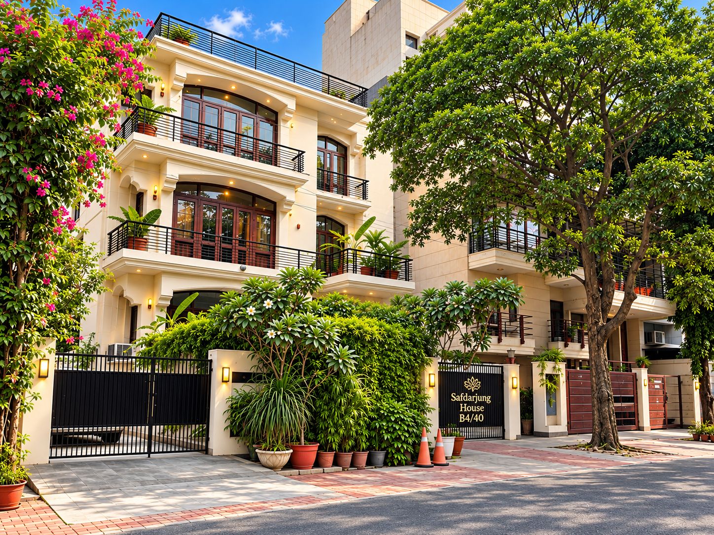 A multi-story hotel with a gated entrance, potted plants, and a sign indicating the name and address.
