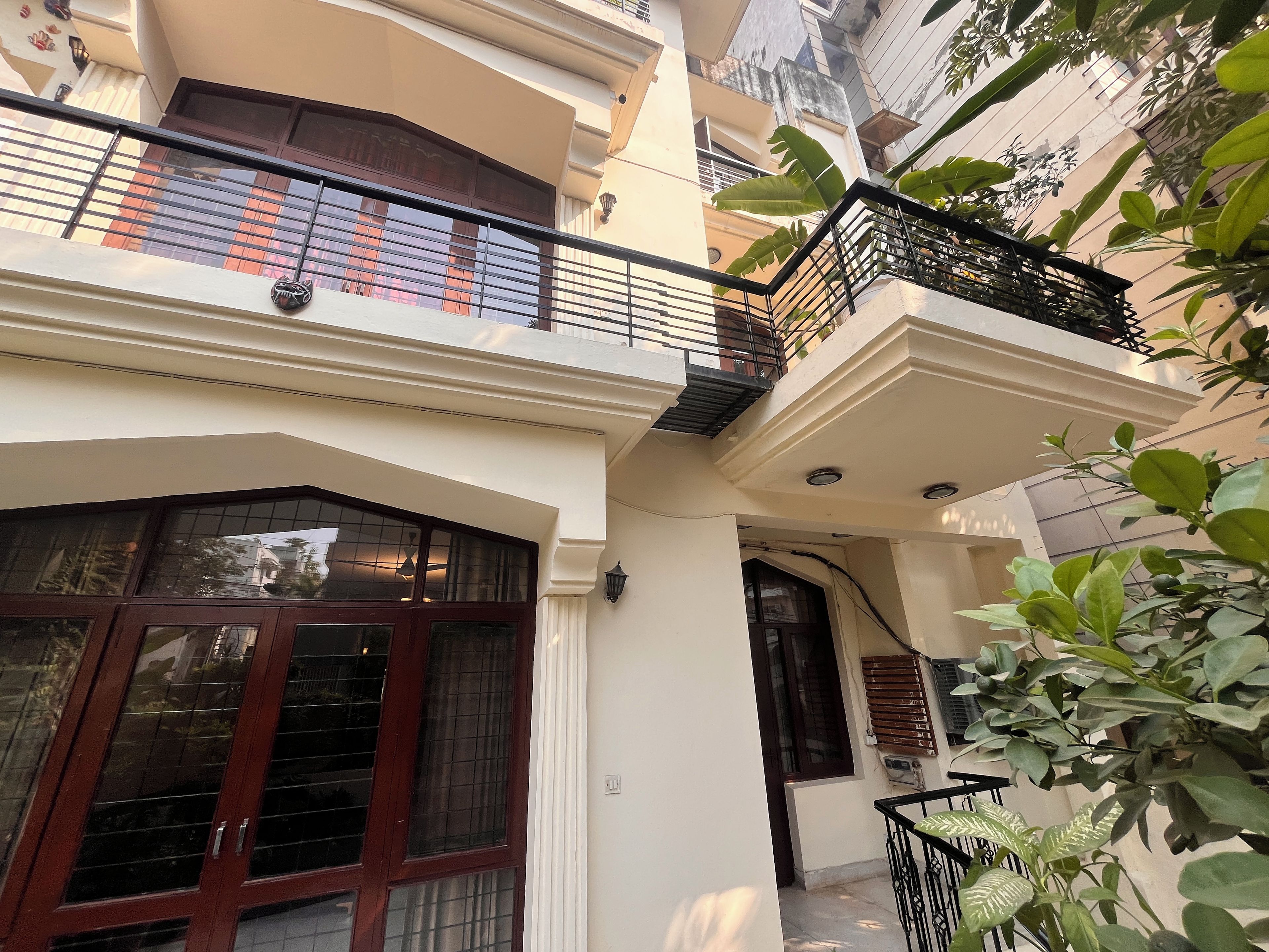 Un edificio residencial con balcón, una ventana de marco oscuro y una planta.