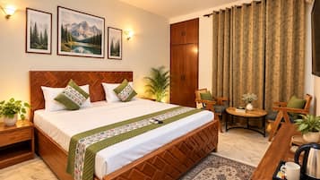 A hotel room with a bed, a desk, a chair, a small table, a plant, a ceiling fan, and curtains.