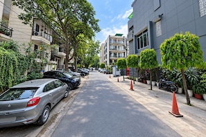 A residential street with parked cars, trees, and buildings. - Safdarjung House (New Delhi)