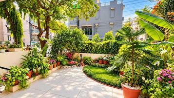 Un jardín bien cuidado con diversas plantas en macetas y un césped impecable.