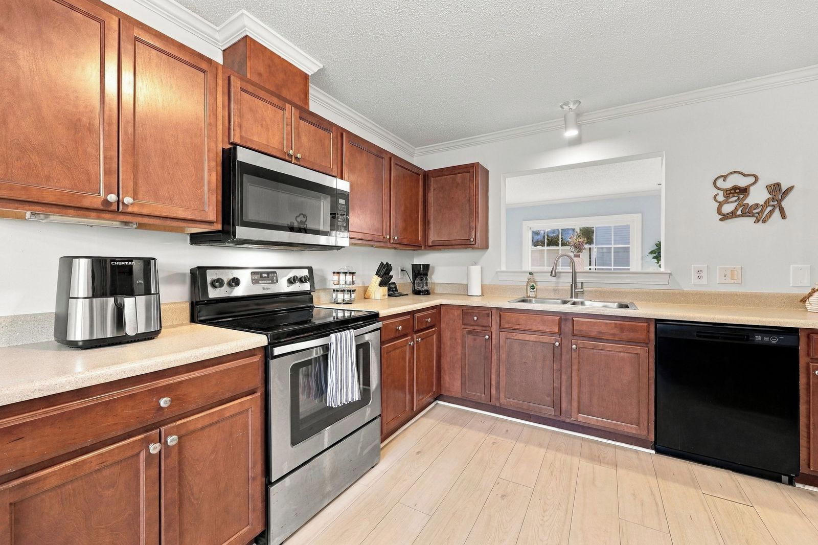 A kitchen with wooden cabinets, stainless steel appliances, a microwave, a stove, and a dishwasher.