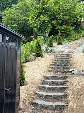 A set of stone steps leading up a hill, surrounded by greenery and a wooden structure. - New Construction Luxury Waterfront Home Olympic Mtn Views & Private Beach (Bremerton)
