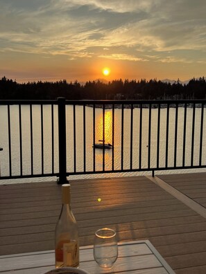 Sonnenuntergangblick von einer Terrasse, mit einer Flasche und einem Glas auf dem Tisch.