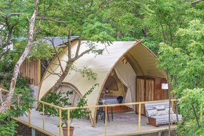 A tented accommodation with a small porch, a table, and a bench.