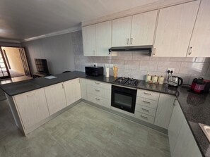 A modern kitchen with a central island, built-in appliances, and light wood cabinetry. - Perfect 2-bedroom apartment in a delightful Cape Town neighbourhood (Cape Town)