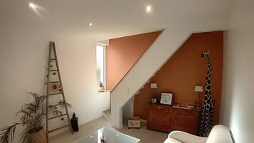 A modern living room with a staircase, a sofa, a coffee table, and a giraffe decoration.