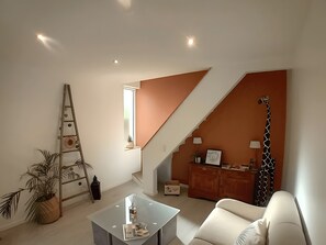 Una sala de estar moderna con una escalera, un sofá, una mesa de centro y una decoración de jirafa.