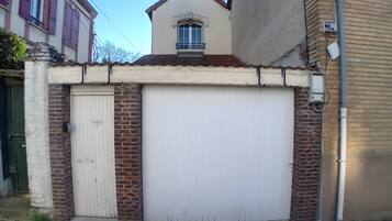 A building with a white garage door, brick walls, and a small balcony with a window.