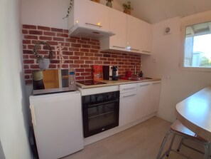 Una cocina compacta con pared de ladrillo, muebles blancos, horno empotrado y una pequeña encimera.