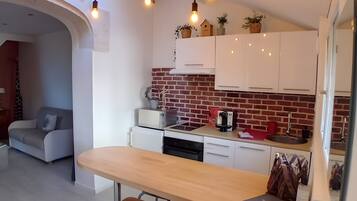A modern kitchen with white cabinets, a brick backsplash, and pendant lighting.