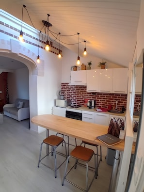 A modern kitchen with white cabinets, a brick backsplash, and pendant lighting. - Holiday Home “La Maison Tandem By Les Étapes” with Private Terrace and Wi-Fi (Chartres)