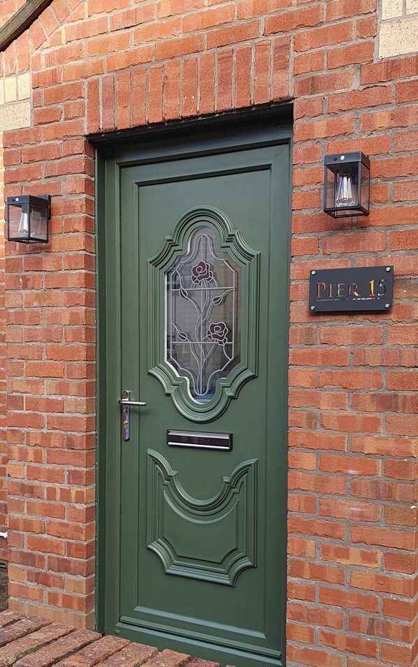 Une porte verte avec un panneau de verre et une plaque en métal portant l’inscription « Pier 13 ».