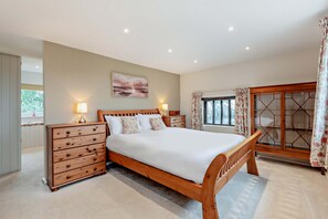 A bedroom with a wooden bed, bedside tables, a large window with curtains, and a view of the outdoors. - Host & Stay | Yeoman's House (Old Wives Lees)