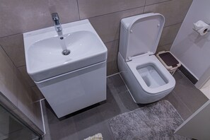 Ein Badezimmer mit einem weißen Waschbecken, einer Toilette und einer kleinen Mülleimer.