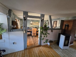 Ein rustikaler Innenraum mit freiliegenden Holzbalken, einem Essbereich mit Tisch und Stühlen sowie einem Kamin.