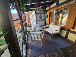 Ein Balkon mit einer Holzpergola, einem weißen Sofa, einem runden Tisch und einer Buddha-Statue.