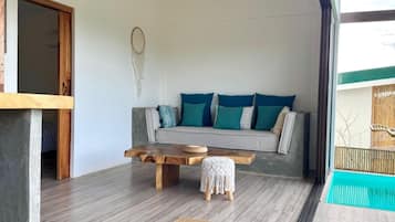 Ein modernes Wohnzimmer mit einer Couch, einem Holztisch und einem Traumfänger an der Wand.