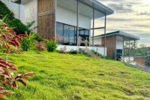 Een modern huis met een grote glazen pui, een schuin dak en een verzorgd gazon.