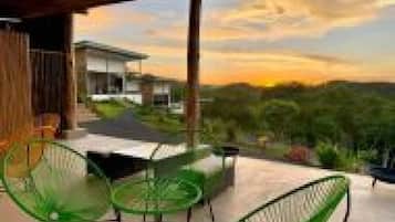 A modern outdoor seating area with a view of a house and landscape.