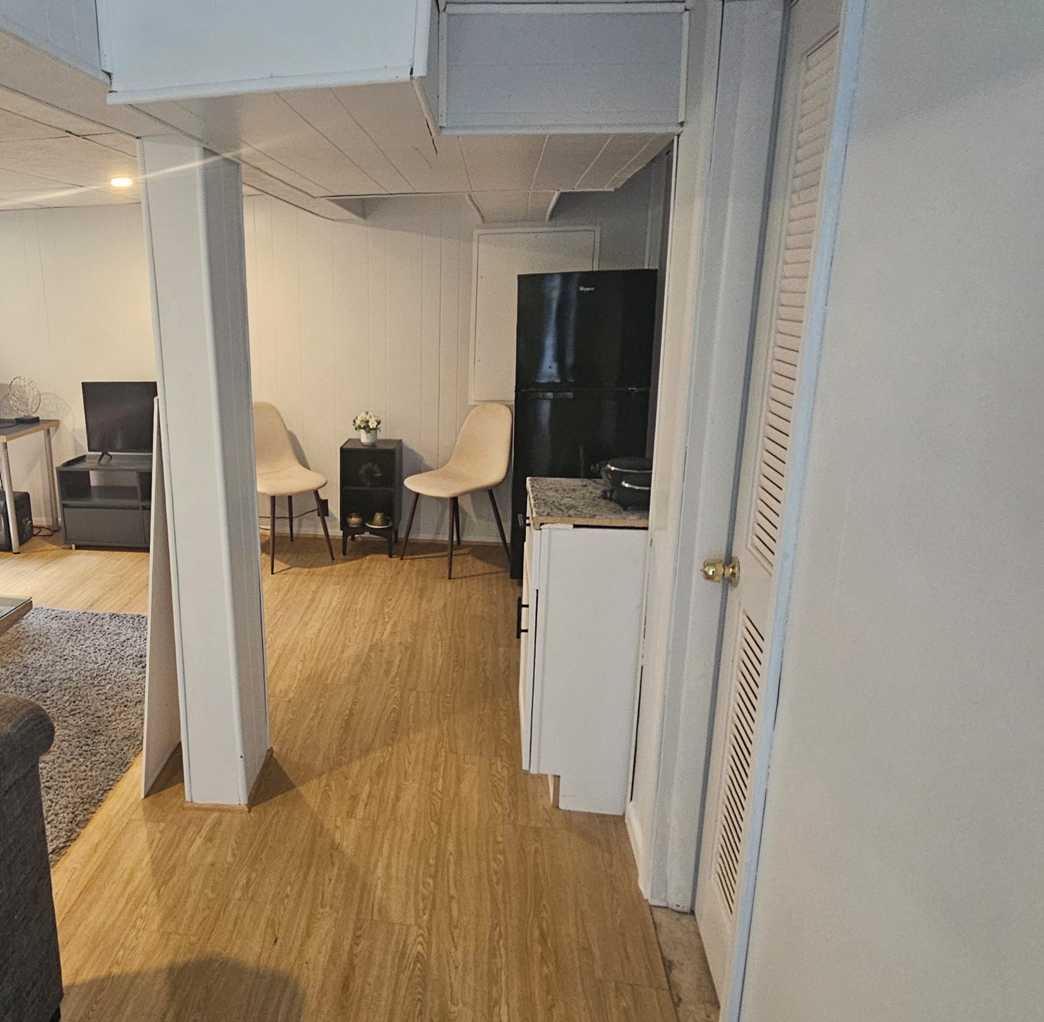 A compact room with a kitchenette, two chairs, a small table, and a television.