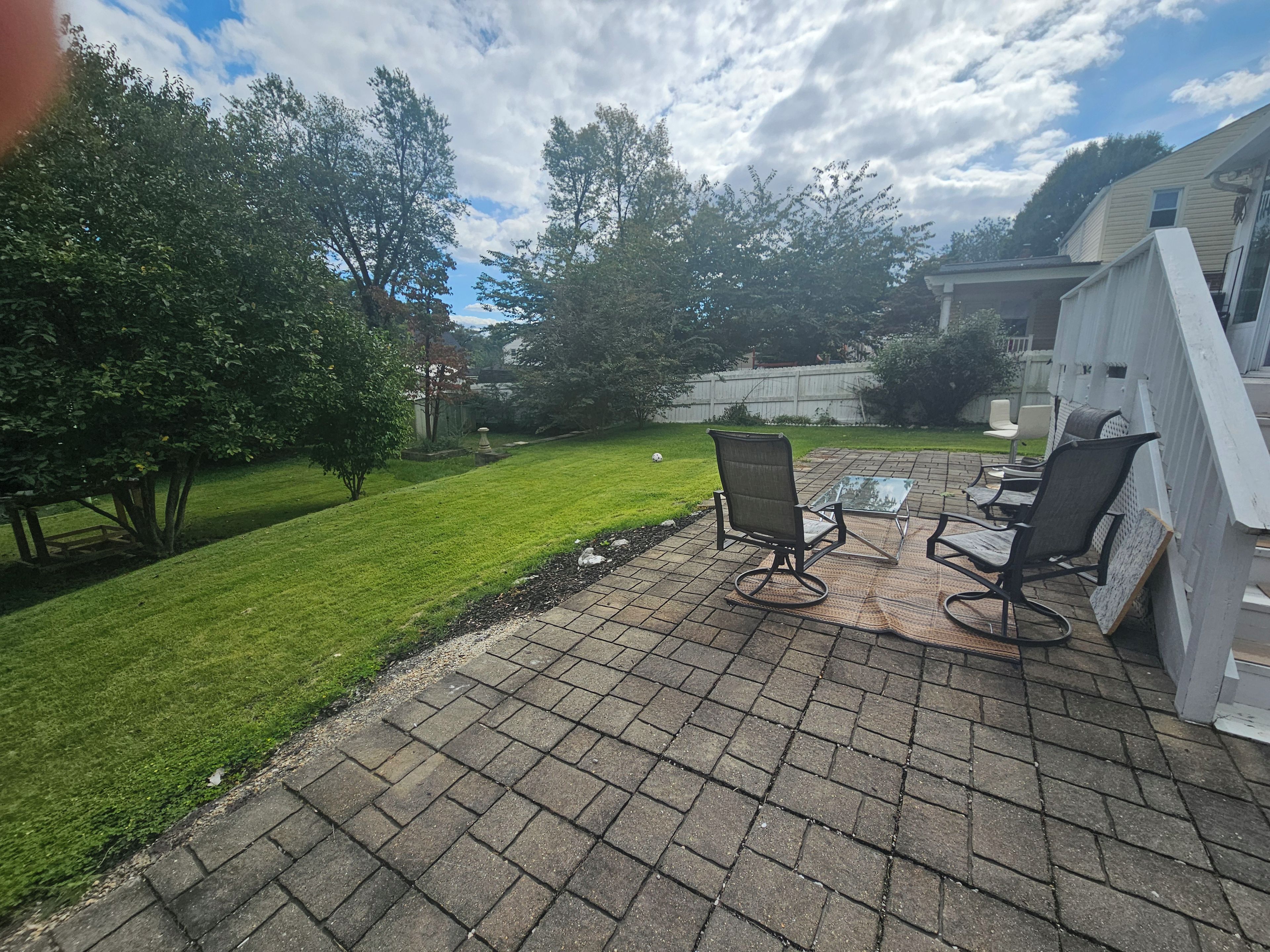 A patio with outdoor furniture, a lawn, and a white fence.
