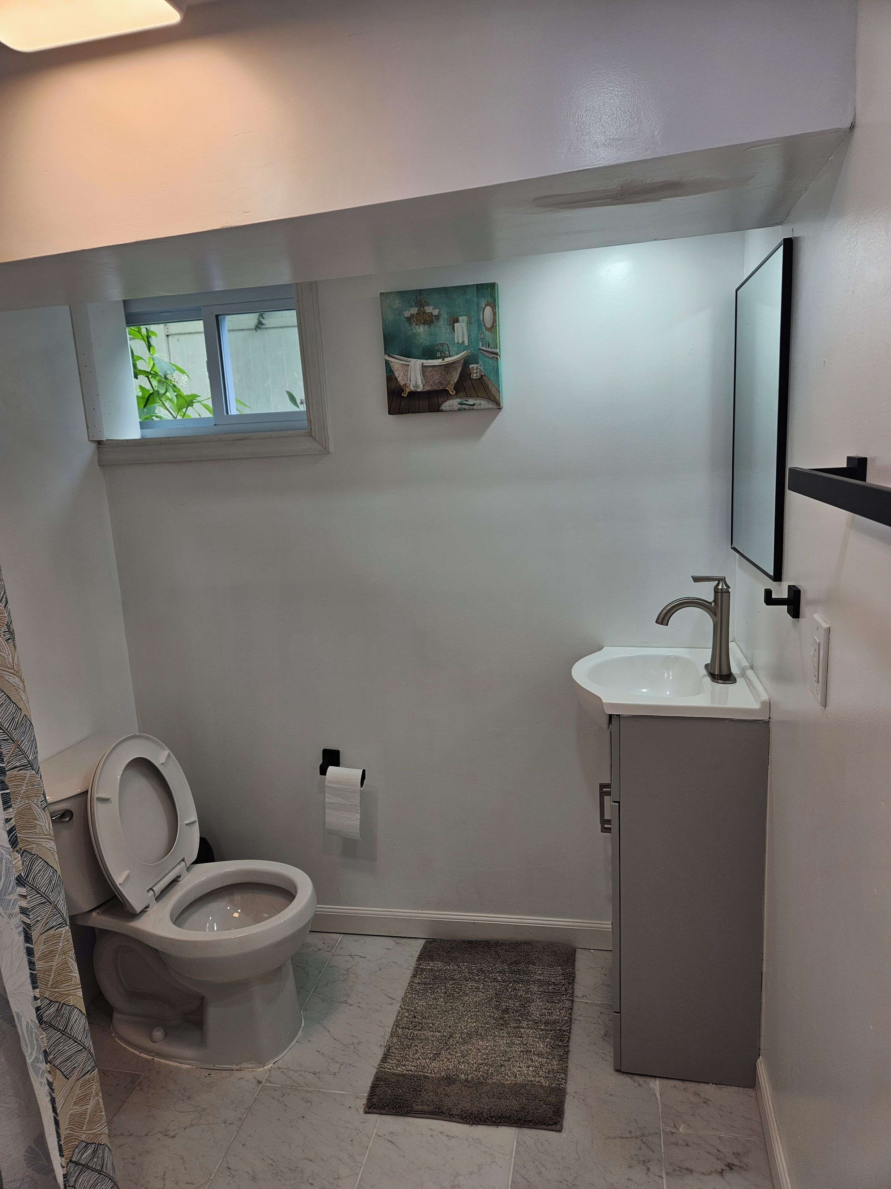 A bathroom with a toilet, sink, and a small window.