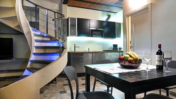 Une cuisine moderne dotée d’un four encastré, d’une table à manger avec des chaises et d’un escalier en colimaçon.