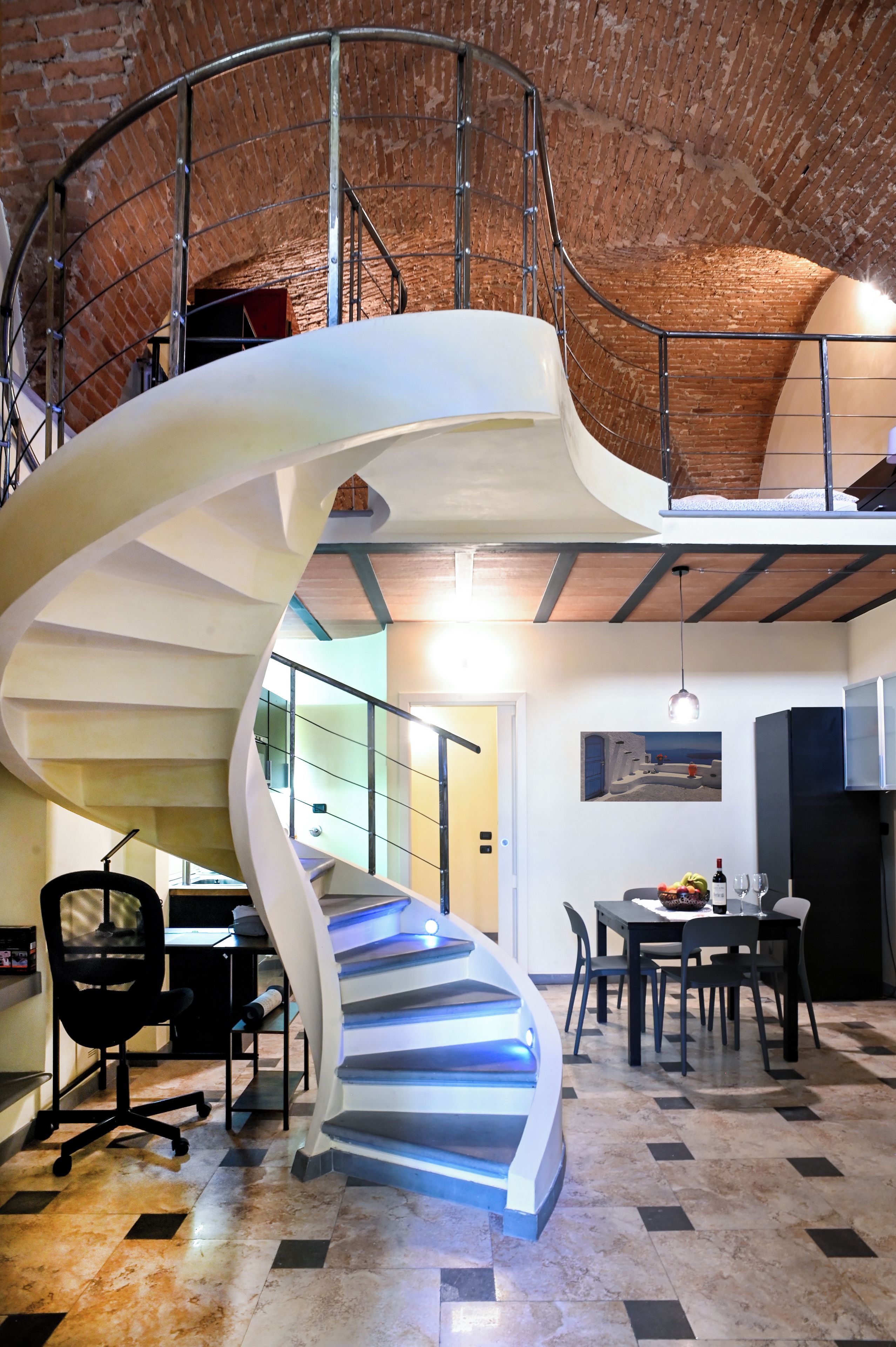 A spiral staircase with a metal railing, leading to an upper level.
