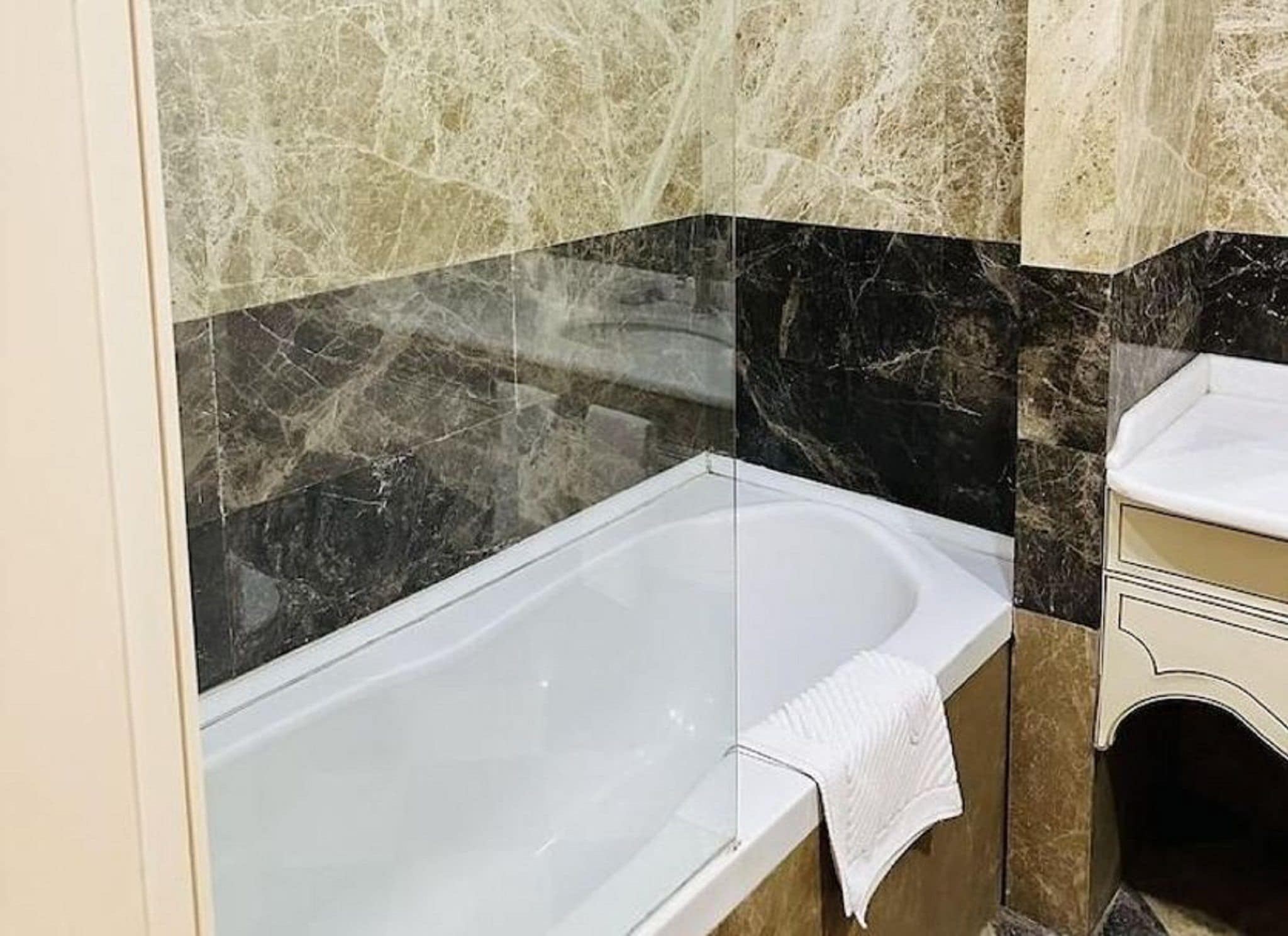 Ein Badezimmer mit einer Badewanne, einem Waschbecken und Marmorwänden.