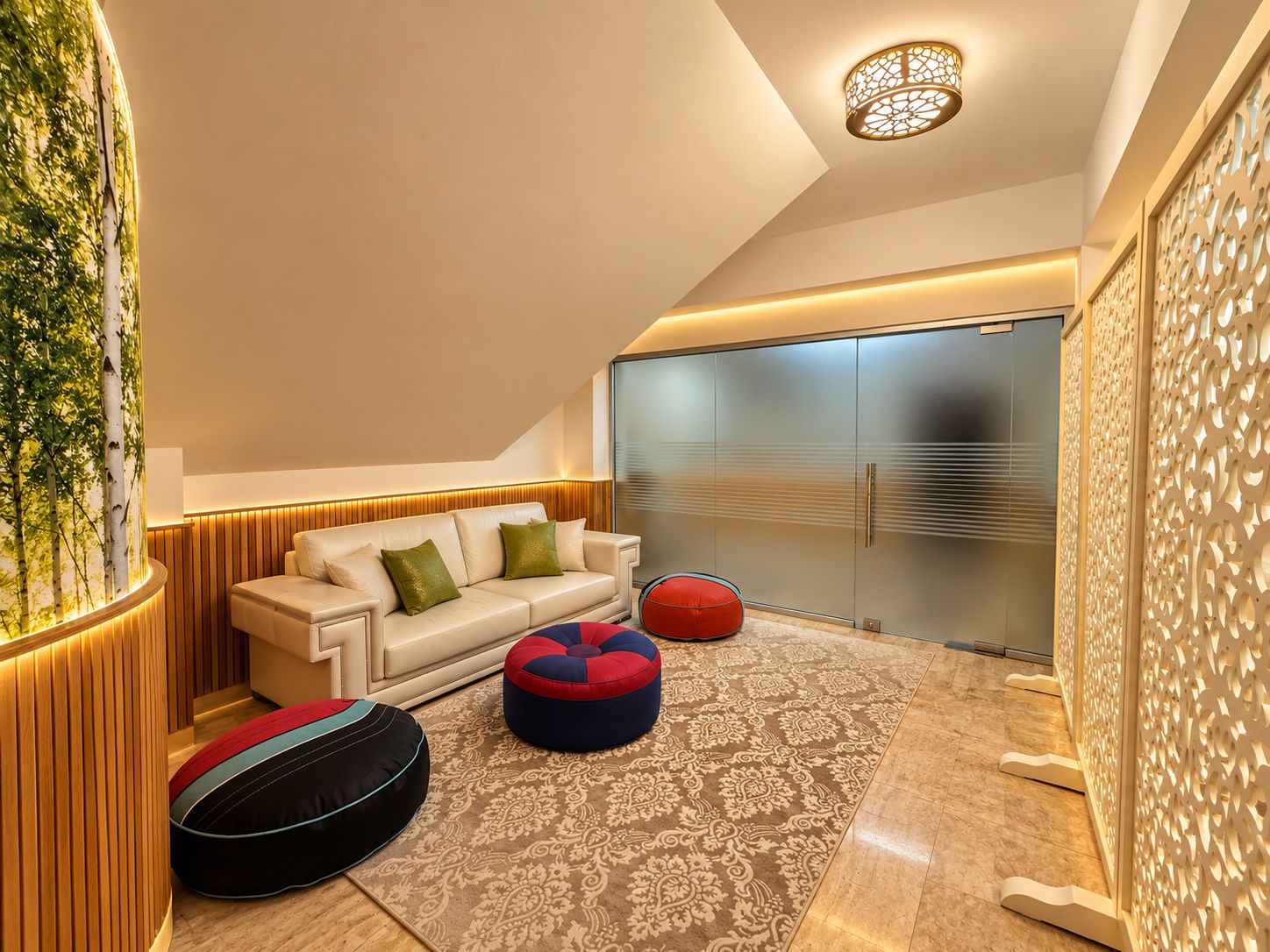 Un salon moderne avec un canapé, des poufs, un tapis à motifs et un luminaire fixé au mur.
