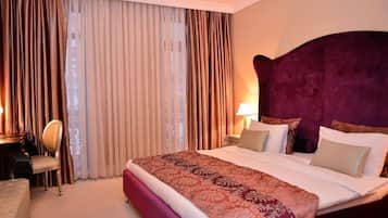 Une chambre d’hôtel avec un grand lit, un bureau avec une chaise et une fenêtre avec des rideaux.