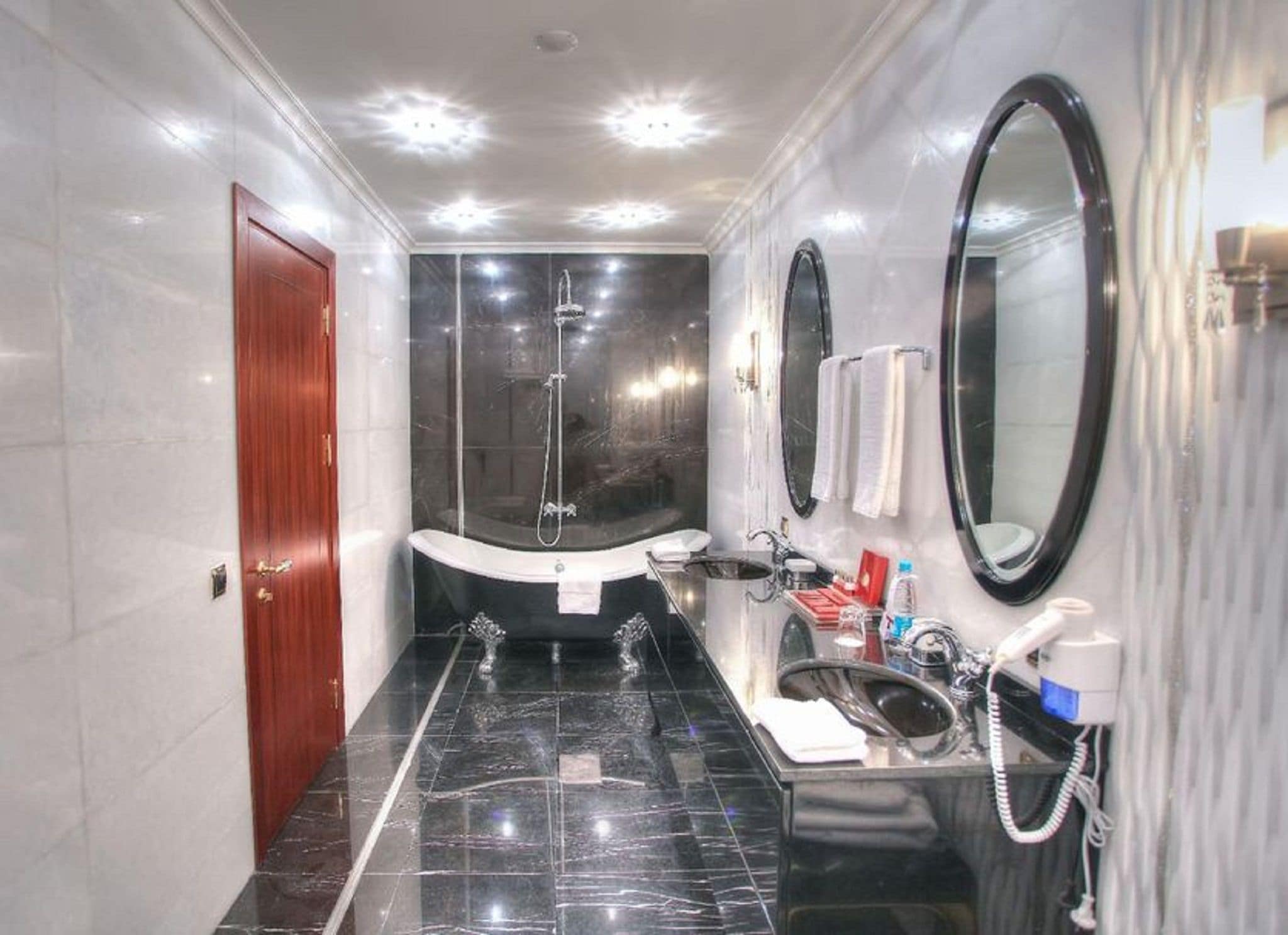 Une salle de bain moderne avec un sol en marbre, une baignoire sur pieds, un lavabo avec un miroir et des toilettes.