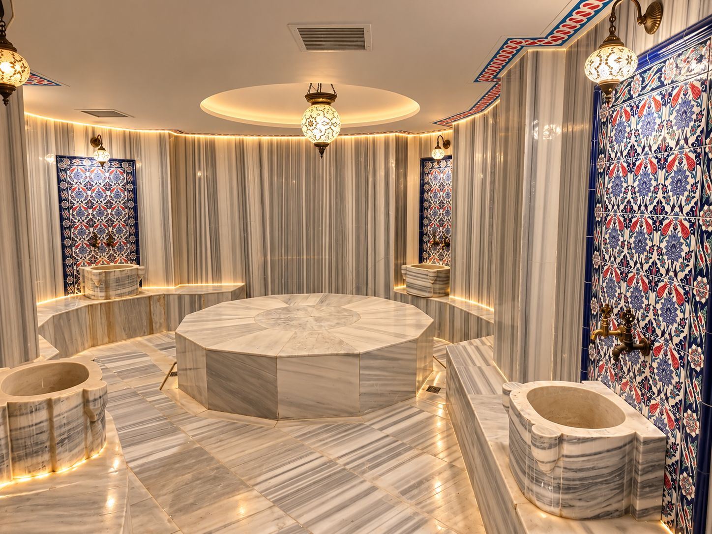 Un baño lujoso con un lavamanos central de mármol, múltiples dispensadores de toallas e iluminación decorativa.