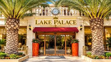 L’entrée du Lake Palace, avec une horloge, des palmiers et un auvent rouge.