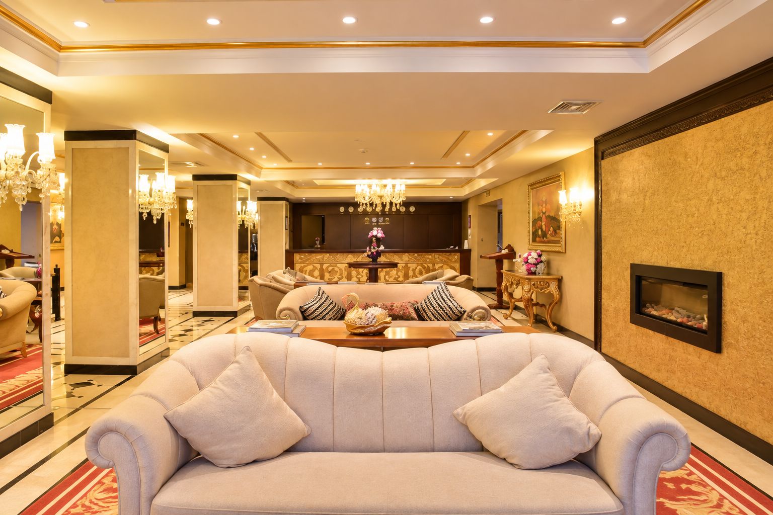 Un salón amplio con un sofá beige grande, una chimenea y un candelabro.
