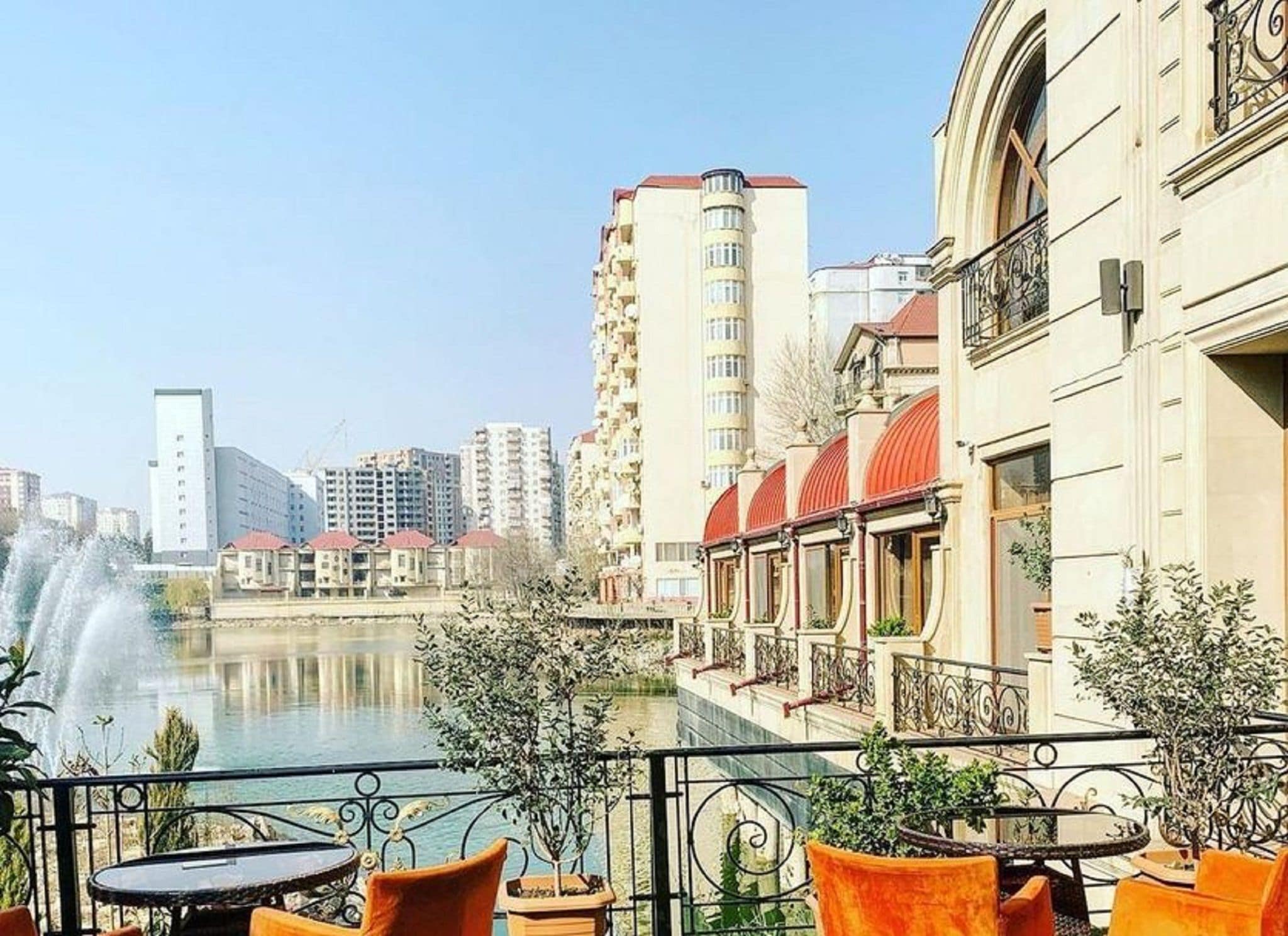A balcony with outdoor furniture overlooking a body of water and buildings.