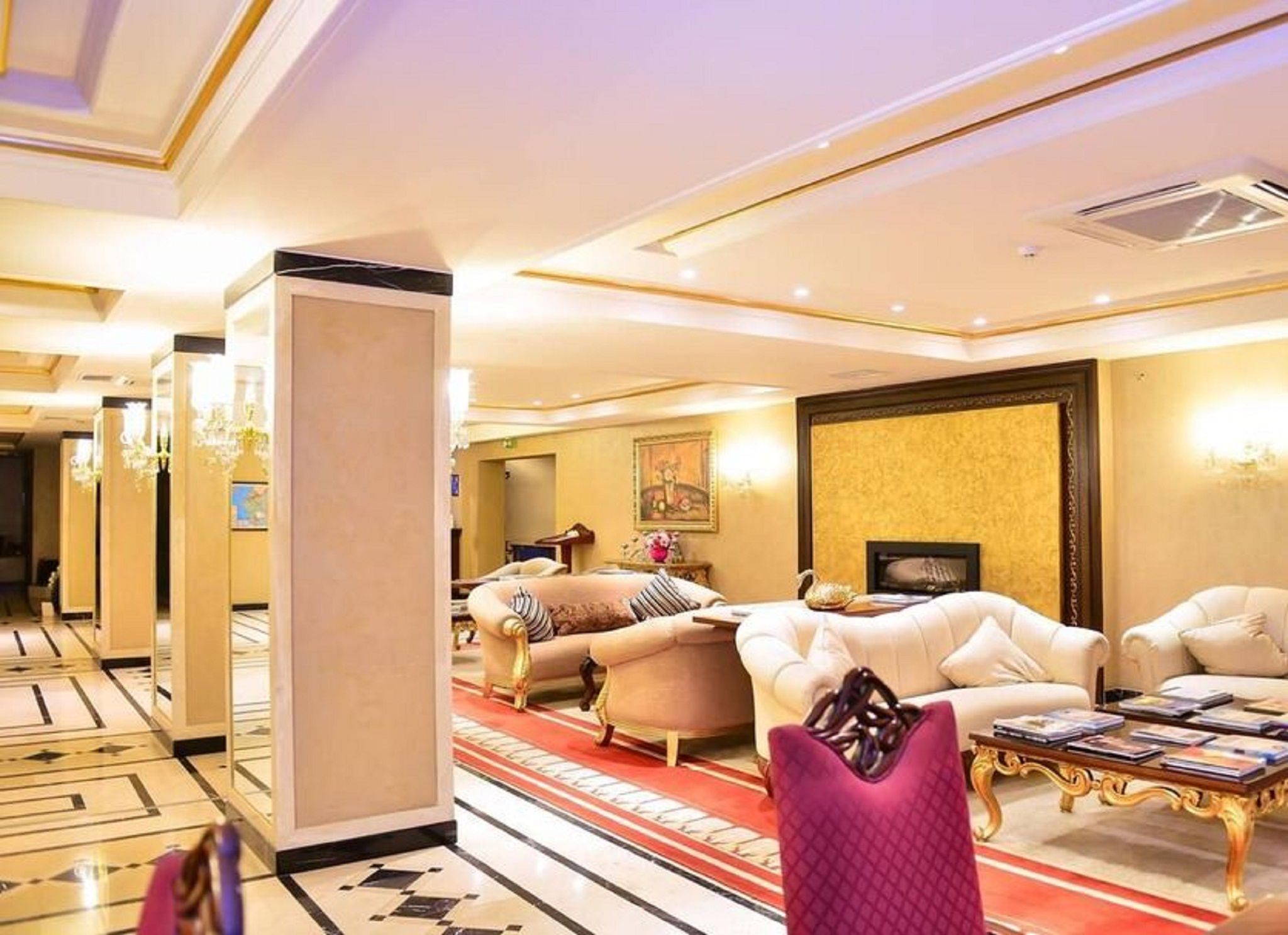 Un amplio vestíbulo de hotel con alfombra roja, asientos cómodos y un candelabro.