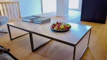 A modern living room with a wooden floor, a coffee table with a bowl of apples, and two books on the table.
